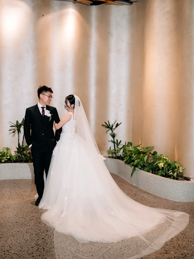 Tà váy cưới dài trải trên lối đi sảnh tiệc, Dâu và chú rể đứng nhìn nhau