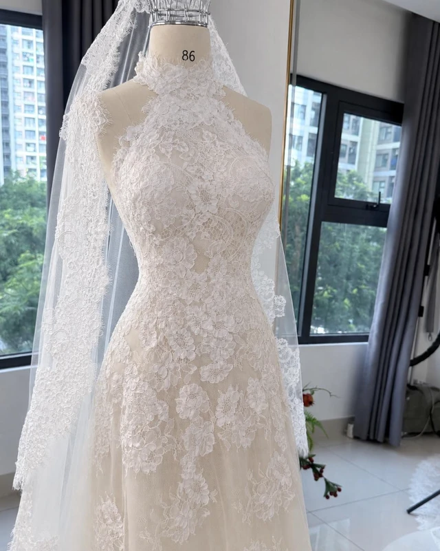 Váy cưới ren gân Pháp cổ cao lót nude trên ma-nơ-canh tại studio LAM'S