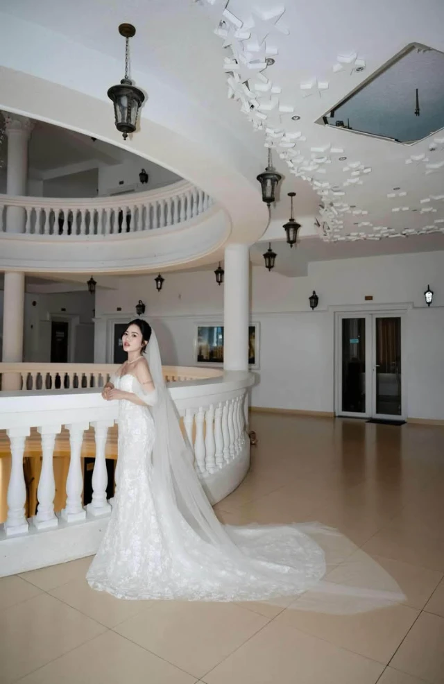 Dâu đứng giữa sảnh cầu thang, đuôi váy ren trải dài phía sau