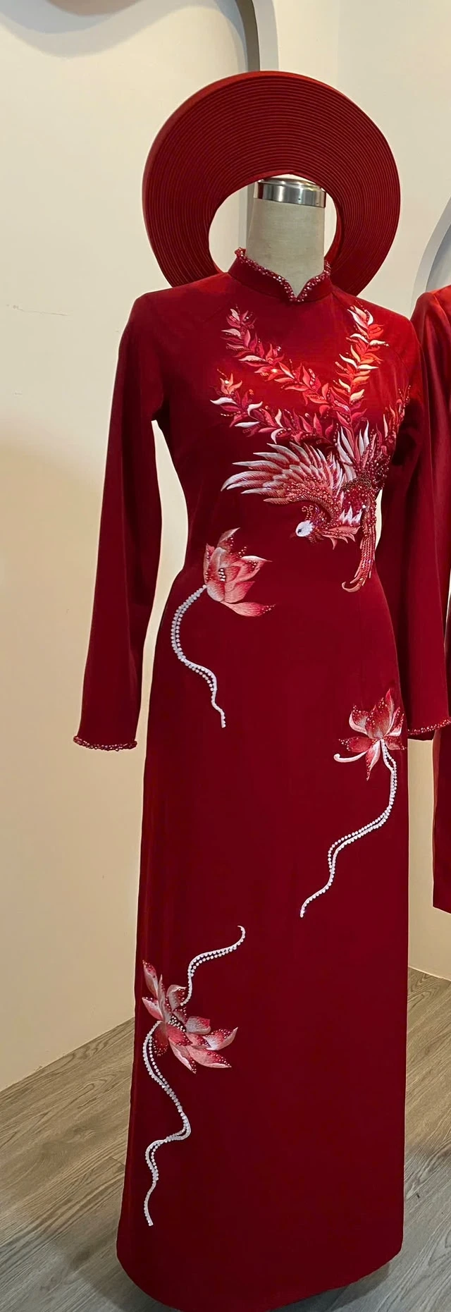 Áo dài cô dâu lụa ruby đỏ trên ma-nơ-canh, đính kết hình phượng dọc thân áo, kèm khăn đóng cùng màu