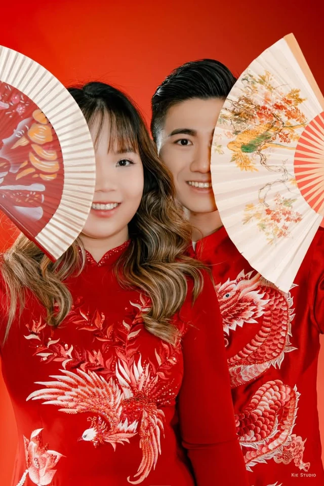 Cô dâu và chú rể cầm quạt giấy, cận cảnh hoạ tiết phượng và rồng đính trên áo dài đỏ