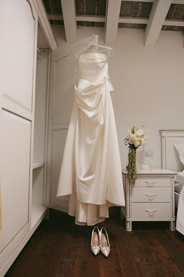 Dâu ở Ý may đo online 2 váy cưới satin cúp ngực off-shoulder Váy cưới satin off-shoulder may đo của LAM'S treo trong phòng cô dâu, phần thân xếp nếp mềm